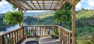 une terrasse en bois avec des plantes en pot et une vue sur la rivière. dans l'établissement Finca El Peñol, à Guatapé