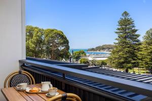 a table on a balcony with a view of the water at Hotel Nelson in Nelson Bay