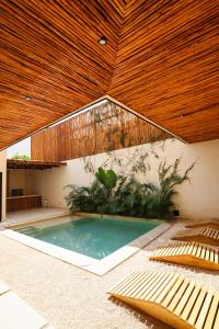 a swimming pool with a wooden ceiling and chairs at Akbal Tulum in Tulum