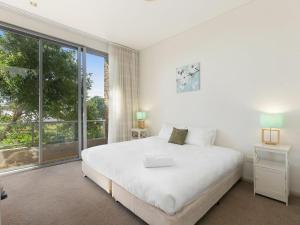 a white bedroom with a bed and a large window at Aqua Viva 2 in The Entrance