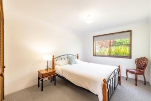 une chambre avec un lit, une fenêtre et une chaise dans l'établissement Casa Carinho, 24 Wallawa Rd - spectacular water views, pet friendly, air con and Wi-Fi, à Nelson Bay