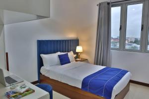 a bedroom with a bed and a desk with a laptop at EMERALD@On320 in Colombo