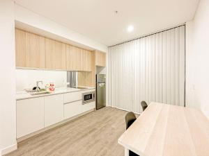 eine Küche mit weißen Schränken und einem Holztisch in der Unterkunft Burword Suites Free Parking in Sydney