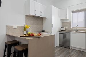 a kitchen with white cabinets and a tray of fruit on a counter at Snow-Berri in Berridale