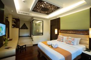 1 dormitorio con 1 cama grande y TV en Peach Hill Resort - SHA Extra Plus, en Kata Beach