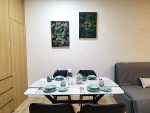 een witte tafel met groene gerechten erop met stoelen bij Kuching City Centre Smart Home Luxury Resort Condo in Kuching