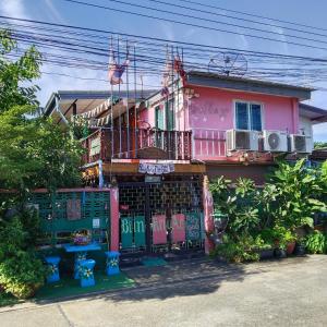 a pink house with a balcony on top of it at Ban Kru Ae HomeHostel in Bangkok