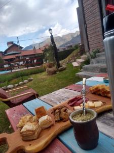 a wooden cutting board with bread and cheese on a table at Gracias Viejo in Merlo