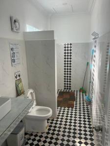 uma casa de banho com WC e piso em azulejo preto e branco em ‘The Greenhouse’ Nesat Village em Phumĭ Chroŭy Svay