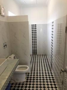 een badkamer met een toilet en een zwart-witte tegelvloer bij ‘The Greenhouse’ Nesat Village in Phumĭ Chroŭy Svay