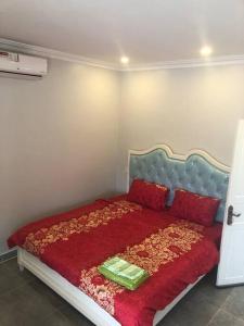 een slaapkamer met een bed met een rode deken en rode kussens bij ‘The Greenhouse’ Nesat Village in Phumĭ Chroŭy Svay