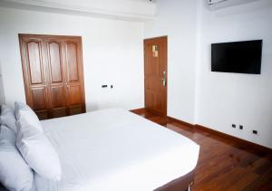 a bedroom with a white bed and a flat screen tv at Hotel Agatalh Pinares Alto Pereira in Pereira