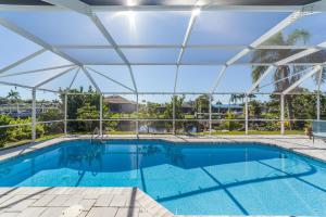 una piscina con techo y una gran piscina en Modern Waterfront Pool Home with Direct Gulf Access, Pet Friendly!, en Cabo Coral