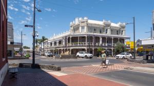 a man crossing a street in front of a white building at Driftwood - Bunbury in Bunbury