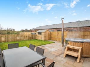 a patio with a table and chairs and a hot tub at Babbling Brook Barn in Abbots Bromley