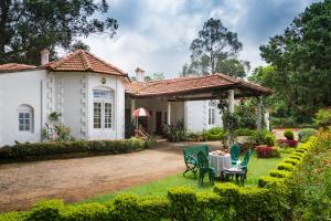 a house with a table and chairs in the yard at Neemrana's Wallwood Garden in Coonoor