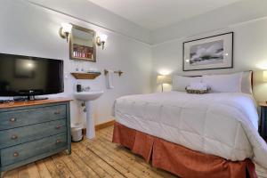 a bedroom with a large bed and a television at Auberge de la Vieille Maison in Rimouski
