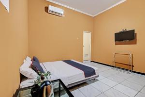 - une chambre avec un lit et une télévision murale dans l'établissement Collection O 92864 Mitra Residence, à Semarang
