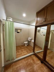 a bathroom with a toilet and a green shower curtain at Aestus Adventure and Wellness Centre in Kasauli