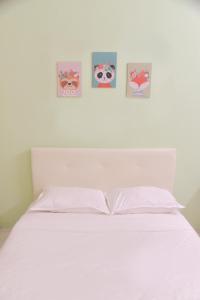 uma cama branca com quatro fotografias na parede em The Karaoke Homes Ipoh, Oldtown em Ipoh