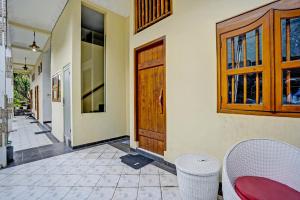 a hallway of a house with a wooden door and chairs at OYO Life 92030 Ef Palm Guest House Family in Surabaya