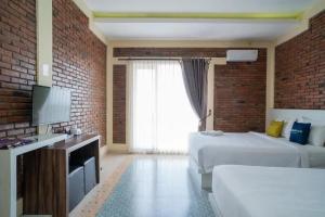 a hotel room with two beds and a television at Urbanview Hotel Omah Anin Batu by RedDoorz in Tlekung