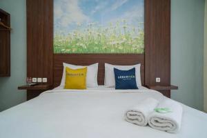 1 dormitorio con 1 cama con toallas en Urbanview Hotel Omah Anin Batu by RedDoorz en Tlekung