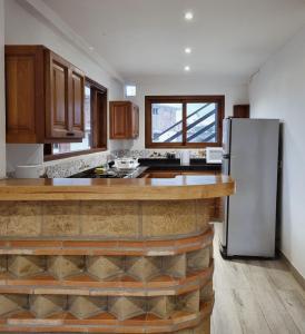 een keuken met een witte koelkast en houten kasten bij El Bosque de la Villa Loft in Villa de Leyva