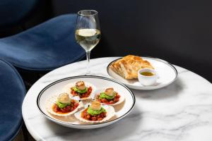 a table with two plates of food and a glass of wine at Crowne Plaza Canberra, an IHG Hotel in Canberra