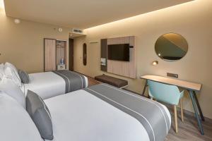 Habitación de hotel con 2 camas y TV en City Express Plus by Marriott Mazatlan en Mazatlán