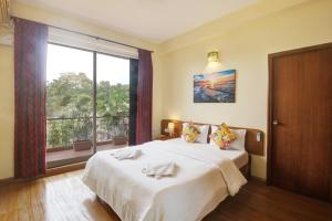 Genesis Leisure - Charming home-stays near Anjuna, Vagator & Assagao في أنجونا: غرفة نوم بسرير ونافذة كبيرة
