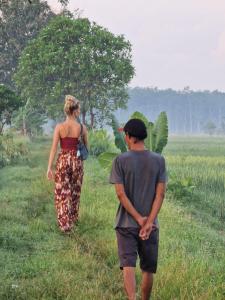 a man and a woman walking through a field at Gado-gado BnB in Yogyakarta