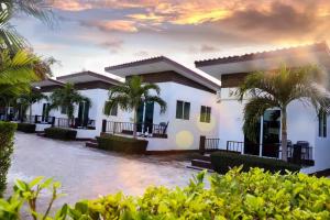 une maison blanche avec des palmiers devant elle dans l'établissement Billabong Golf Club & Resort, à Nong Prue