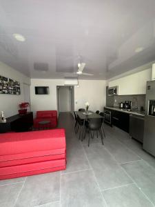 uma sala de estar com um sofá vermelho e uma cozinha em Casa Mariposa em Herradura