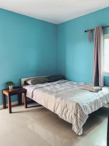 a blue bedroom with a bed and a table at Parida Resort in Sing Buri