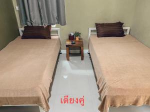 Parida Resort في سنغ بوري: سريرين يجلسون بجانب بعض في غرفة