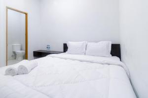 a large white bed with white sheets and pillows at Limo Depok Residence RedPartner in Depok