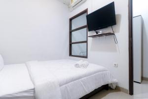 a bedroom with a bed with a tv on the wall at Limo Depok Residence RedPartner in Depok