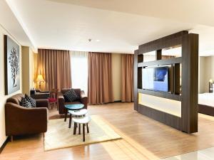 une chambre d'hôtel avec une télévision et un salon dans l'établissement Swiss-Belhotel Pangkalpinang, à Pangkal Pinang