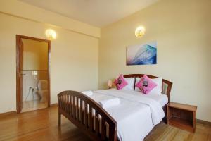 Genesis Leisure - Charming home-stays near Anjuna, Vagator & Assagao في أنجونا: غرفة نوم مع سرير أبيض كبير مع وسائد وردية
