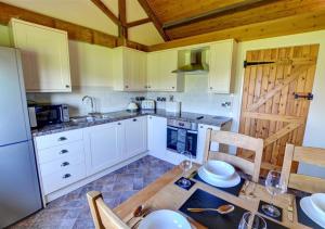 LlandinamにあるCorlanのキッチン(白いキャビネット、テーブル、椅子付)