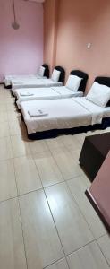 a row of beds lined up in a room at Destiny Riverside Hotel in Kota Bharu