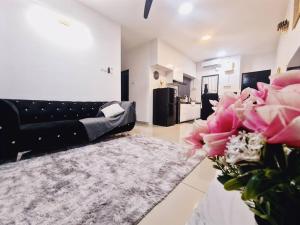 a living room with a black couch and pink flowers at New! 4-7pax 2bedrooms condo near Mount Austin JB in Johor Bahru