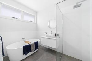 a white bathroom with a tub and a sink at Hamptons by Khove in Gold Coast +15 photos