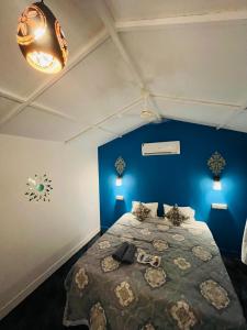 1 dormitorio con 1 cama con pared azul en LAKSHDEEP COTTAGES en Canacona
