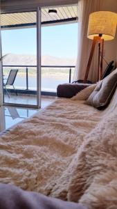 a bed in a room with a large window at Departamento frente a lago Carlos Paz - Villa Siquiman - Complejo Veneto Village in Villa Parque Siquiman
