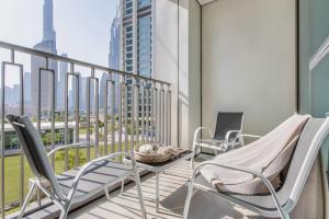 Frank Porter - Downtown Views II T2 في دبي: شرفة مع كرسيين وطاولة على مبنى