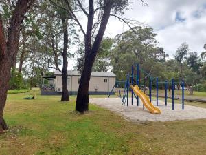 a playground with a slide in a park with trees at Mt Barker Holiday Park - Western Australia in Mount Barker