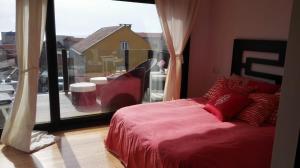 um quarto com uma cama vermelha e uma grande janela em duplex de lujo en medio del paraiso em Teira