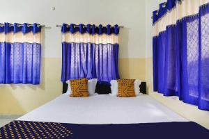 een slaapkamer met blauwe gordijnen en een groot bed bij OYO Hotel Yamuna Banquet & Resort in Dhanbad